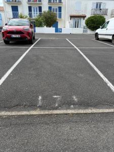 a parking lot with a red car parked in it at Studio cosy les Sables d'Or in La Guérinière
