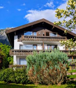 a house in the mountains with a tree at T13 Ferienwohnungen Schenk in Oberstdorf