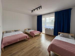 a room with two beds and a window with blue curtains at Apartamenty Piotrowice in Piotrowice +71 photos