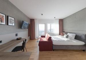 a bedroom with a bed and a couch and a window at Brera Serviced Apartments Singen in Singen