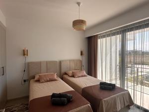 two beds in a room with a large window at Mykonos Homes Cyprus in Kyrenia +12 photos
