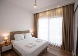 a bedroom with a bed with white sheets and a large window at Aqualina D5-1 by HolidayKeys in Kyrenia +15 photos