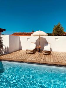 a patio with two chairs and an umbrella next to a swimming pool at Villa between forest and ocean in Labenne