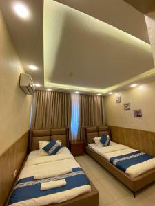two beds sitting in a room with a window at Al Mansi hotel in Amman