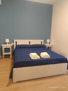 a bedroom with a bed with blue sheets and two tables at dante 55 in Agrigento