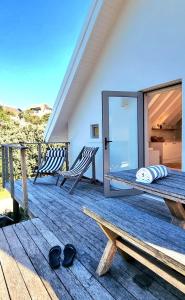 a deck with two chairs and a bed and some sandals at St Francis Cottage close to beach in St Francis Bay