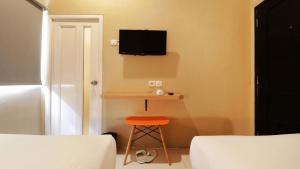 a room with a stool and a tv on the wall at Hotel Quds Express Syariah in Jakarta