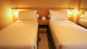 two beds in a small room with a desk at Hotel Quds Express Syariah in Jakarta