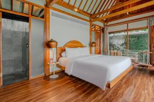 ein Schlafzimmer mit einem weißen Bett und einem großen Fenster in der Unterkunft Ayom Java Village Solo in Solo
