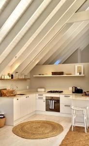 an attic kitchen with white cabinets and a rug at St Francis Cottage close to beach in St Francis Bay