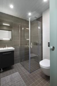 a bathroom with a shower and a toilet and a sink at Arkkitehtihuvila järvinäköalalla 5 makuuhuonetta ja tilauspalveluna ulkoporeallas in Ähtäri