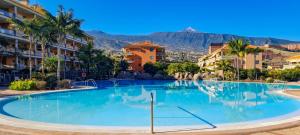 a large swimming pool with palm trees and buildings at Jardín del Teide in Puerto de la Cruz