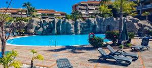 a pool at a resort with chairs and a rock wall at Jardín del Teide in Puerto de la Cruz