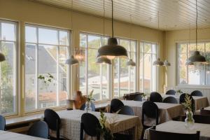 a dining room with tables and chairs and windows at Hotel Villa Lejet in Tisvilde