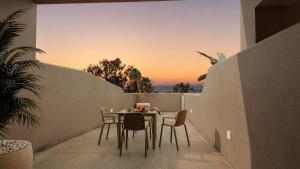 a table and chairs on a balcony with the sunset at Terracotta Sunset Suites in Oia