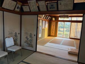 a room with a door and two chairs and a window at 麻心家azamiya in Nagao
