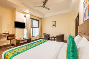 a bedroom with a bed and a desk and a tv at Treebo Ivy Castle in Gurgaon +40 photos