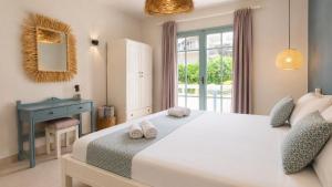 a bedroom with a large white bed and a blue desk at Kurmulis Studios in Stalos