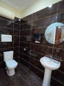 a bathroom with a toilet and a sink and a mirror at ATB Grand Hostel in Atyrau +11 photos