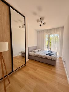 a mirror in a bedroom with a bed and a window at Marina Augustów - BRYZA in Augustów