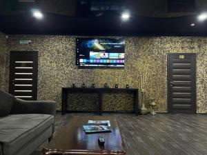 a living room with a couch and a tv on a wall at ATB Grand Hostel in Atyrau