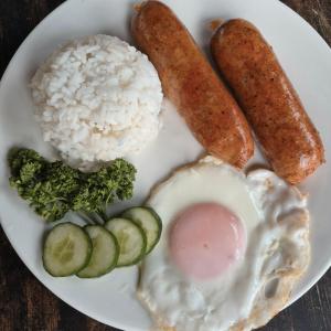 a plate of food with rice and sausage and vegetables at Beachfront Aircon Kubo for 4pax in Caba