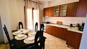 a kitchen with a table and chairs with plates and bowls at Villa Galani Afitos in Afitos +3 photos