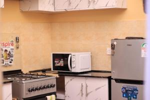a kitchen with a stove and a microwave at BomaZuri Homestays Tala in Nguluni