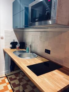 a kitchen counter with a sink and a microwave at Au petit Chapeau Rouge in Clisson