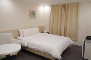 a bedroom with a white bed and a chair at Hotel Azure Incheon in Incheon