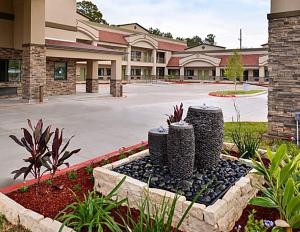 a front view of a hotel with a courtyard at Scottish Inn & Suites - Conroe in Conroe