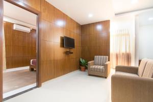 a waiting room with a tv and a couch and a chair at Shoba Tulip Hebbal in Bangalore