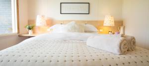 a bedroom with a large white bed with two lamps at Beeches By The Sea in Apollo Bay
