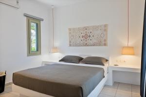 a white bedroom with a bed and two lamps at Lagadia Village in Antiparos