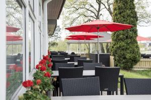 a row of tables and chairs with red umbrellas at Scandic Norrköping Nord in Norrköping