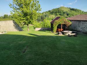 a yard with a stone wall and green grass at Vazsita ház in Erdőbénye