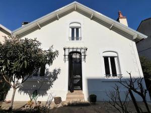 a white house with a black door and windows at villa des roses in Bergerac