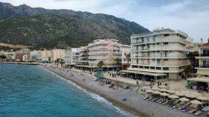 a beach with umbrellas and buildings and the ocean at Votsala in Loutraki