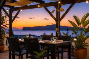 a dining table with a view of the ocean at sunset at Kurmulis Studios in Stalos +39 photos