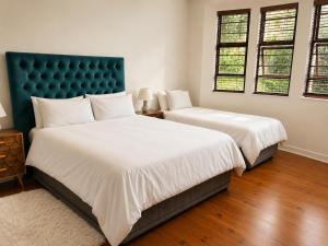 a bedroom with two beds with white sheets and a blue headboard at Serenity Stay- Walmer in Gqeberha