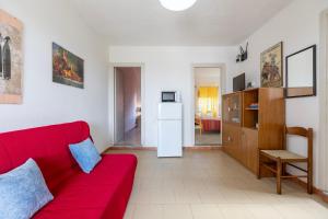 a living room with a red couch and a kitchen at Villa Rosa Sea View in Valledoria