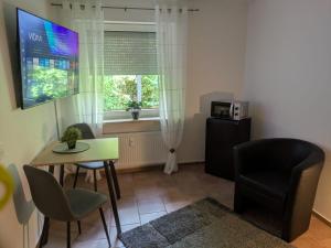 a living room with a table and chairs and a television at Lutz Appartements Südheide - Einzelzimmer in Gifhorn