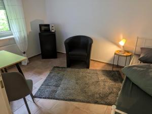 a living room with a black chair and a table at Lutz Appartements Südheide - Einzelzimmer in Gifhorn