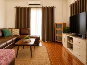 a living room with a couch and a flat screen tv at Pai Local Apartment in Pai