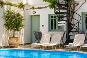 a group of chairs and a ladder next to a pool at Kurmulis Studios in Stalos