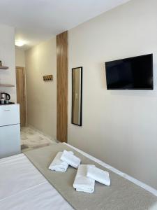 a bedroom with two towels on a bed with a flat screen tv at Olympic Beach Rooms in Olympic Beach