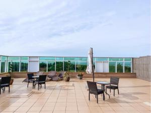 a patio with chairs and tables and an umbrella at SPA Amber Palace in Šventoji