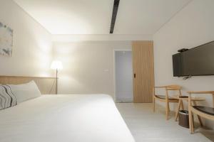 a hotel room with a bed and a flat screen tv at Feng-Chi Inn in Taitung City