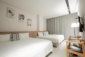 a hotel room with two beds and a chair at Feng-Chi Inn in Taitung City