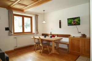 a dining room with a table and a tv on the wall at Sesvennahof in Malles Venosta